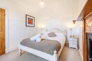 a bedroom with a white bed and a fireplace at Braich-Y-Celyn Lodge in Aberdyfi