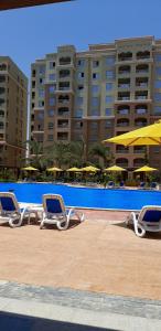 two lounge chairs sitting next to a pool with umbrellas at Studio apartment, Aqua View Resort, North coast in El Alamein