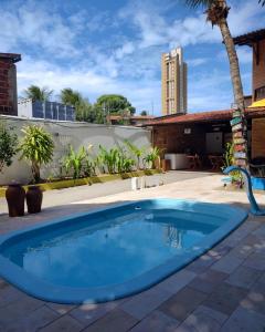 una piscina en un patio con un edificio en Pousada Flor D' Açucena, en Natal