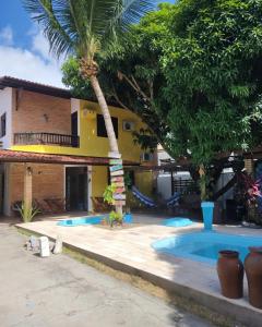una casa con una piscina y una palmera en Pousada Flor D' Açucena, en Natal