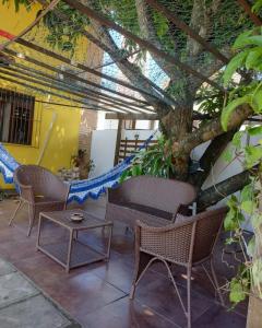 un patio con sillas, una mesa y un árbol en Pousada Flor D' Açucena, en Natal