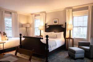 a bedroom with a bed and a chair and windows at OneSixtyFive, The Inn on Park Row in Brunswick