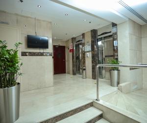 eine Lobby mit Treppen und einem TV an der Wand in der Unterkunft Al Sharq Hotel Suites - BAITHANS in Schardscha