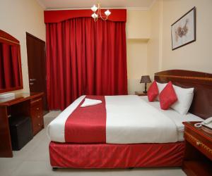 a bedroom with a large bed with red curtains at Al Sharq Hotel Suites - BAITHANS in Sharjah +28 photos