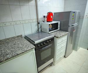a small kitchen with a stove and a microwave at Al Sharq Hotel Suites - BAITHANS in Sharjah