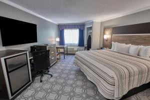 a hotel room with a bed and a flat screen tv at Ambassador Inn and Suites in South Yarmouth