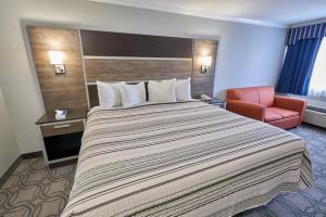 a hotel room with a large bed and a chair at Ambassador Inn and Suites in South Yarmouth