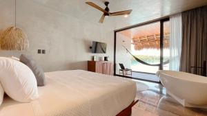 a bedroom with a bed and a tub and a window at Hotel Amainah Bacalar Adults Only in Bacalar