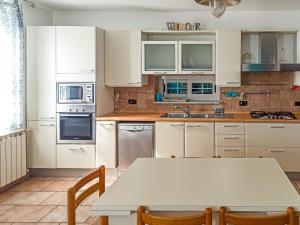 cocina con armarios blancos y mesa en La Casa di Anna ☆☆☆☆☆[Cogoleto - 100 metri dal MARE], en Cogoleto