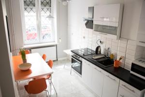 uma cozinha com armários brancos e uma mesa com cadeiras laranja em Private rooms in the Old Town em Gdansk