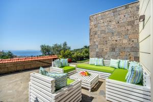 een terras met groen-witte meubels tegen een bakstenen muur bij Villa green Eden in Sorrento