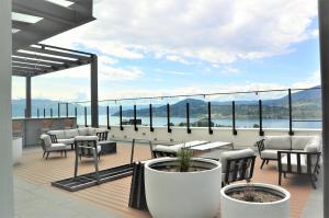 a balcony with tables and chairs and a view of the water at WOW Penthouse 22nd Floor Downtown Lakeview in Kelowna