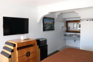a bedroom with a bed and a tv and a dresser at El Dorado Motel in Gardena