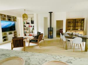 a living room with a table and chairs and a television at Villa- Vaux sur mer -200 m plage Nauzan - Piscine in Vaux-sur-Mer