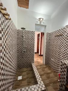 a bathroom with a shower and a tile wall at Amos House in Kendwa