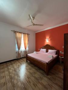 ein Schlafzimmer mit einem Bett mit einer orangefarbenen Wand in der Unterkunft Amos House in Kendwa
