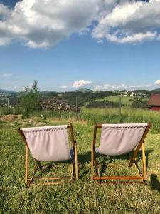 two chairs sitting in the grass in a field at Domek do wynajęcia SkoSki in Jaworzynka