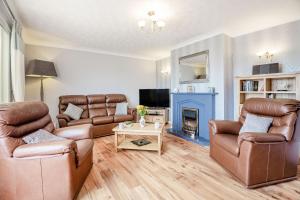 a living room with two couches and a fireplace at Cororion Cottage in Benllech