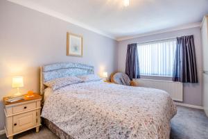 a bedroom with a large bed and a window at Cororion Cottage in Benllech