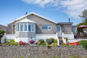 a house with a stone fence in front of it at Cororion Cottage in Benllech