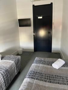 two beds in a room with a black door at Tattersalls Hotel in Goulburn