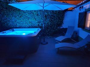 a jacuzzi tub with an umbrella and a chair at Solar da Cavalariça in Ourique