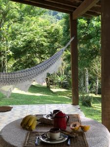 a table with a hammock and a plate of food at Tranquilidade e boa localização na Mata Atlântica in Paraty