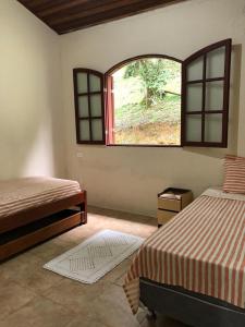 a bedroom with two beds and a large window at Tranquilidade e boa localização na Mata Atlântica in Paraty