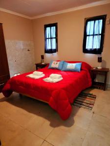 Cette chambre comprend un grand lit rouge et des fenêtres. dans l'établissement Departamento Sarmiento, à Rosario de la Frontera