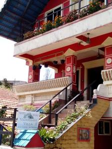 a red building with stairs and flowers on it at VAISHNAVI VILLA-WiFi-Home Food-Family Only-Kitchen Access-No TV in Madikeri