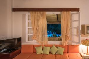 an orange couch in a living room with a window at Marina's Villas in Vasilikos