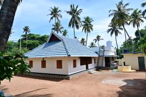a house with a blue roof with palm trees at Kollakudy HomeStay in Paravūr