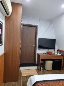 1 dormitorio con puerta de madera y escritorio con TV en Hotel Trí Lê, en Cao Lãnh