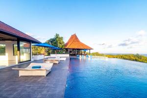 a pool at a resort with chairs and umbrellas at Surya Melasti Exclusive Beach Villa by Sajiwa in Ungasan