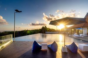 a pool with chairs and an umbrella on top of a house at Surya Melasti Exclusive Beach Villa by Sajiwa in Ungasan