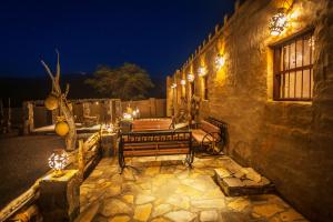 a stone patio with a bench and lights at night at Canyon Rest House Jabal Shams in Al Ḩamrāʼ