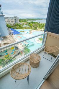 a balcony with three chairs and a view of a pool at Solea Palm Resort Mactan in Mactan