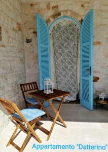 een tafel en stoelen in een kamer met blauwe luiken bij Ramasole in Ostuni