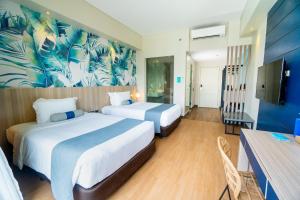 a hotel room with two beds and a tv at Solea Palm Resort Mactan in Mactan