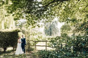 Una novia y un novio parados frente a una valla en Country Retreat at Judd's Folly en Faversham