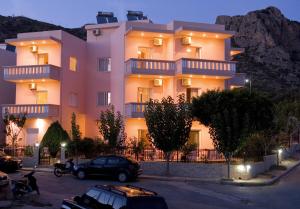 a large pink building with cars parked in a parking lot at Margarita Αpartments Sea View in Palaiochóra