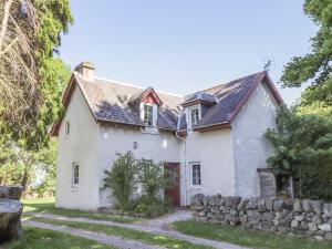 an old white house with a stone wall at Garden Cottage in Elgin