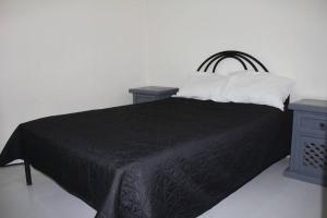 1 dormitorio con 1 cama negra y 2 almohadas en Cerca de Parque industrial Nava 3 hab (Facturable), en Ciudad Obregón