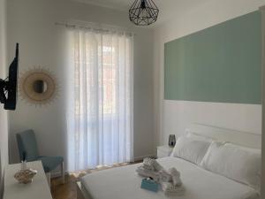 Dormitorio blanco con cama, mesa y ventana en VERDE Ridi Che Ti Passa, en Alassio