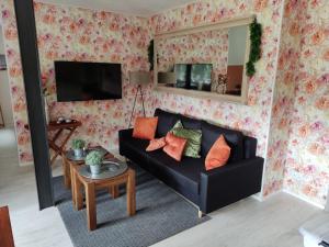 a living room with a black couch and floral wallpaper at Gasthaus Düther Schleuse in Düthe