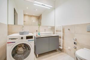 ein Badezimmer mit einer Waschmaschine und einem Waschbecken in der Unterkunft BRIGHT: Rosenheim Aicherpark in Rosenheim