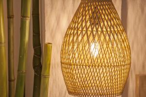 a yellow lamp hanging from a wall next to some bamboo at Paris Studios & Apartment in Agia Paraskevi