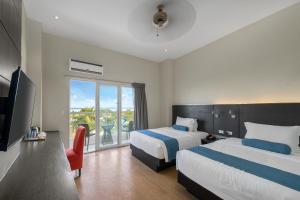 a hotel room with two beds and a balcony at Solea Seaview Resort in Mactan