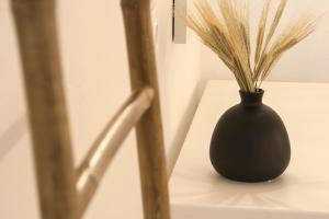 a black vase with grass in it sitting on a table at Paris Studios & Apartment in Agia Paraskevi