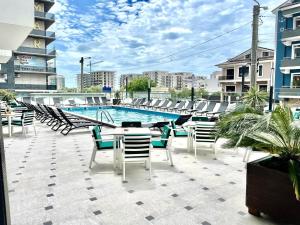 eine Terrasse mit Tischen und Stühlen neben einem Pool in der Unterkunft Havana Studio-Alezzi Nord 10 (piscina&loc parcare) in Năvodari